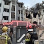 तेहरान में इजरायली हमले के बाद क्षतिग्रस्त इमारत के सामने खड़े अग्निशमनकर्मी